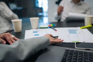 Closeup of business meeting table with analytics documents and hands writing notes during strategic planning session