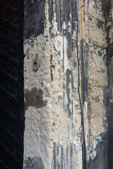 Close up of weathered stone wall with peeling paint and a metal fixture.
