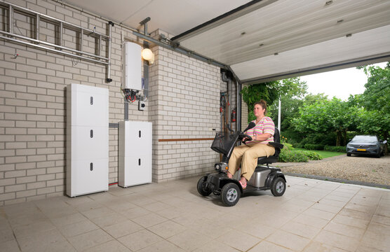 Person using scootmobile in garage with battery storage for surplus electricity