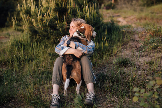 Woman sitting outdoors hugging beagle dog during hiking in nature