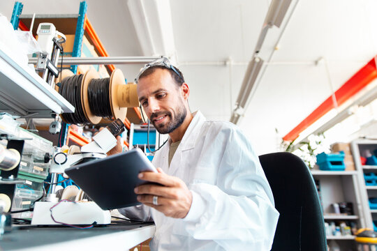 Lab technician inspecting microchip in high tech electronics workspace