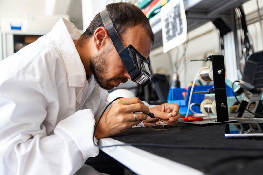 Lab technician soldering microchip in electronics workshop