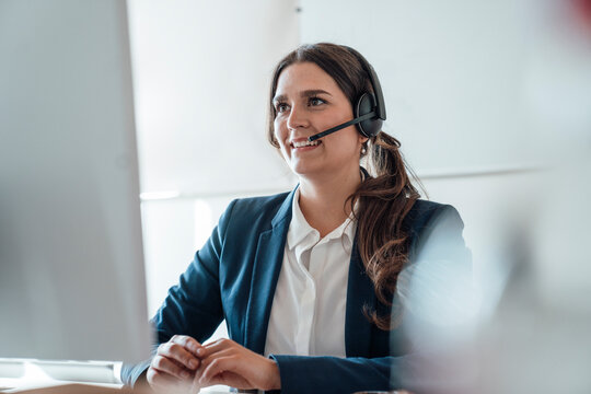 Businesswoman with headset in office providing customer service