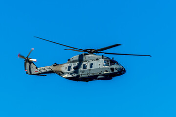 Military helicopter in the air on blue sky background. Gray patrol helix close up. Naval helicopter vehicle flying.