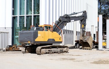 Heavy excavator at work outside a modern building under construction