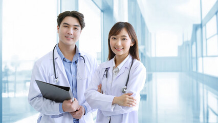 Medicine and healthcare concept : Happy and cheerful asian doctors, Male and Female holding files with stethoscope and smiling in lobby of hospital.