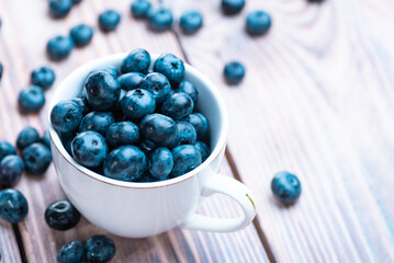 Fresh blueberries in a white cup on a wooden table