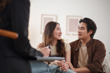 Asian couple talking with psychologist for relationship counseling and family planning, showing trust, understanding, and emotional connection.