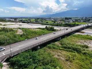 A bridge over a river with a city in the background. The bridge is very long and has a lot of cars on it