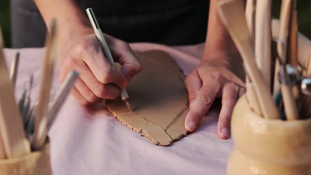Ceramic artist cuts designs into clay with steady precision 4k video. Pottery Cutting Clay Close-up. Cutting clay precise patterns using shaping tool during the early stages of ceramic artistry.