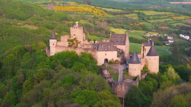 bourscheid castle ch&acirc;teau de green valley hills behind walls black domed towers flag top foggy day tall colorful trees beautiful to left around right drone panning 