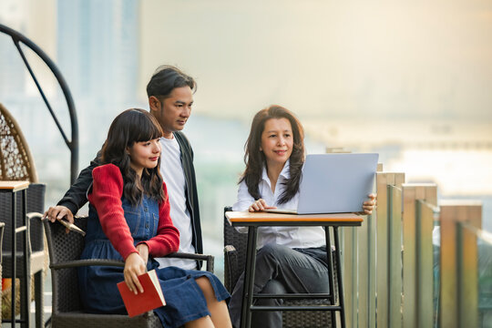 Happy multiracial people relaxing in chair on roof terrace of hotel or office building, using electronic gadgets, laptop, meeting together. - Powered by Adobe