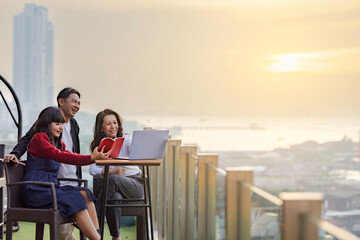 Diverse group of Smiling business colleagues using laptop discussing work and sharing moment of laughter while travel the sea on vacation. Aerial view Nature beautiful light sunset or sunrise over sea