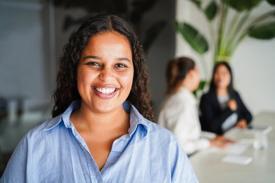 African american young business woman smiling on camera inside corporate office - Female entrepreneurs and digital nomad concept - Focus on face - Powered by Adobe