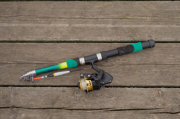 Close-up of a folding fishing rod lying on a wooden background
