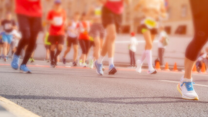 A group of runners are running on a road with a blurry background. Scene is energetic and active