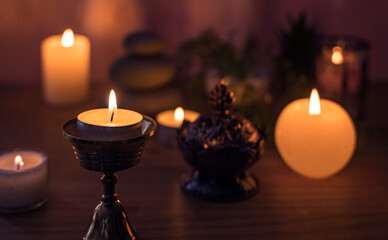 A candle in the foreground and other blurred decorative objects in the background. Candles lit at night. Spa decorative objects.