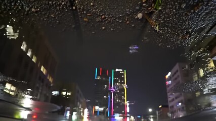 Upside-down night cityscape reflected in a puddle on a wet, stony street