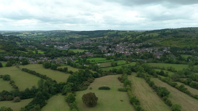 Aerial view of green fields and a town nestled amongst trees, creating a beautiful contrast of nature and civilization, Matlock, England, United Kingdom.