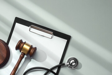 Judge gavel with stethoscope on clipboard close-up on soft green background with sunlight from the...