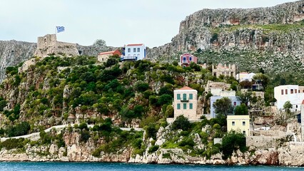 Kastellorizo Megisti, Greece: Ferry view of colorful houses, mountains, and sea in foreground. Summer vacation, Mediterranean travel, Greek island, coastal landscape, scenic seaside, summer holiday 