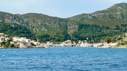 Kastellorizo Megisti, Greece: Ferry view of colorful houses, mountains, and sea in foreground. Summer vacation, Mediterranean travel, Greek island, coastal landscape, scenic seaside, summer holiday 