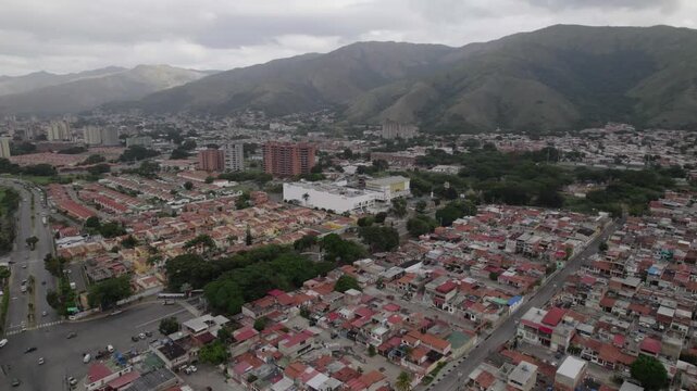 breathtaking drone shot dollies in to capture the peaceful coexistence of a bustling city and the majestic, green mountain range that surrounds it.
