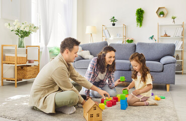 Happy family playing blocks together at home. Young parents play learning game with carefree...