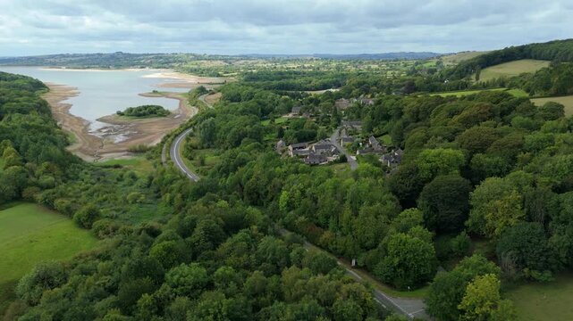 Aerial view of Ladybower Reservoir, framed by lush green trees and winding roads, reveals a picturesque landscape, Matlock, England, United Kingdom.