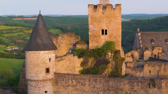 bourscheid castle ch&acirc;teau de green cover hills walls towers flags upper exterior old ruins historical site to left around right up close drone panning 