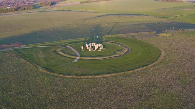 Aerial view of Stonehenge, a prehistoric monument surrounded by green fields, casting long shadows in the landscape, Salisbury, England, United Kingdom.
