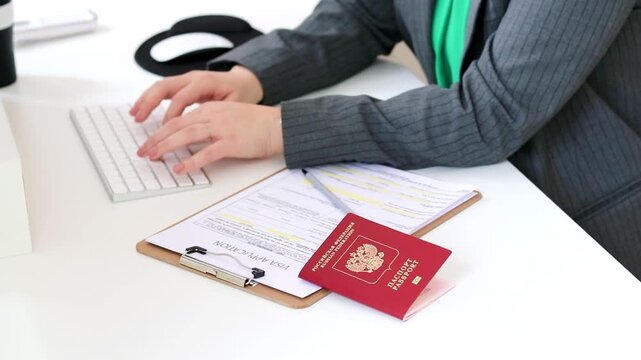 Close up of a caucasian woman filling out visa application document with a Russian passport on a office table