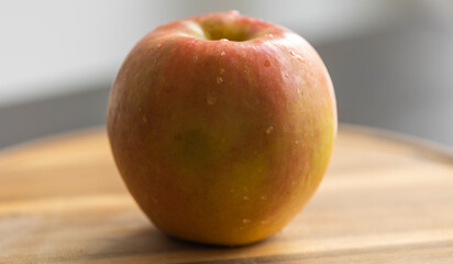 whole fresh crispy apple on wooden cutting board close up