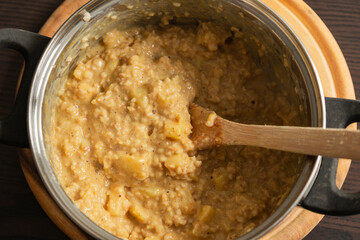 creamy pumpkin oatmeal with apple slices in a cooking pot
