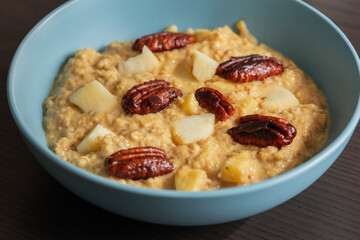 creamy pumpkin oatmeal topped with fresh apple slices and caramelized pecans
