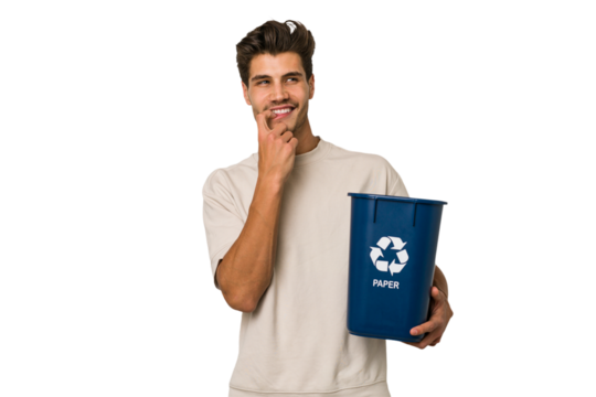 Young caucasian man holding a paper trash for recycle relaxed thinking about something looking at a copy space.