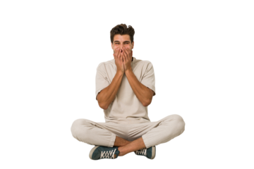 Young caucasian man sitting on the floor isolated on white background laughing about something, covering mouth with hands.