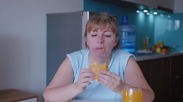 A woman sitting at the kitchen table eating homemade pie with gusto