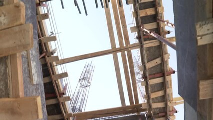 Ascending view of rough concrete stairs and interior of a construction site showing adjustable metal props, temporary scaffolding, and wooden planks supporting the structure. - Powered by Adobe