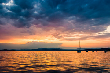 Golden sunset over a serene Aegean sea, with gentle waves and clouds illuminated by the warm evening glow.