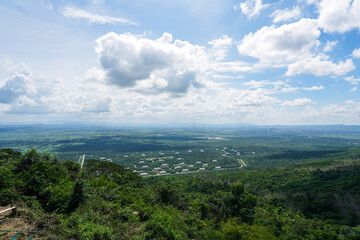 A landscape featuring trees and hills. The image captures an outdoor scene with clouds in the sky, grass covering the ground, and various types of vegetation such as trees and shrubs.