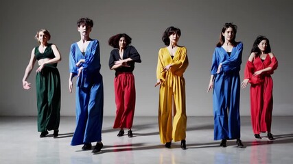 Group of diverse performers in colorful costumes dancing together. Modern dancers executing a synchronized routine in a minimalist studio - Powered by Adobe