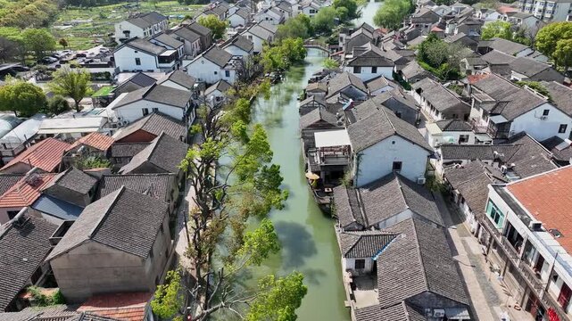 Aerial view of a canal winding through Jinxi, lined by traditional buildings with dark roofs and white walls, creating a picturesque scene, Jinxi, Jiangsu, China.
