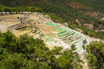 Aerial view of Baishuitai, the White Water Terraces near Shangri-La, Yunnan, China. Natural limestone pools filled with turquoise water among forested mountain slopes