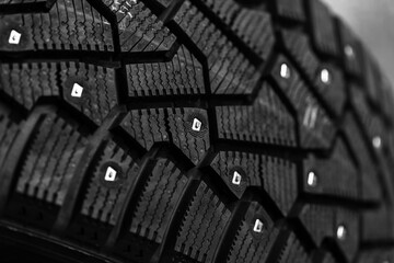 A brand new black studded car tire with metal studs embedded within the tread