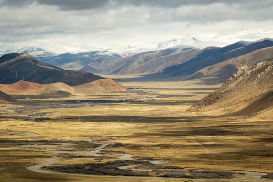 Tibet aerial view Expansive landscape of the Tibetan Plateau with snow-capped mountains and arid valleys under dramatic skies. Remote wilderness at the roof of the world  - Powered by Adobe