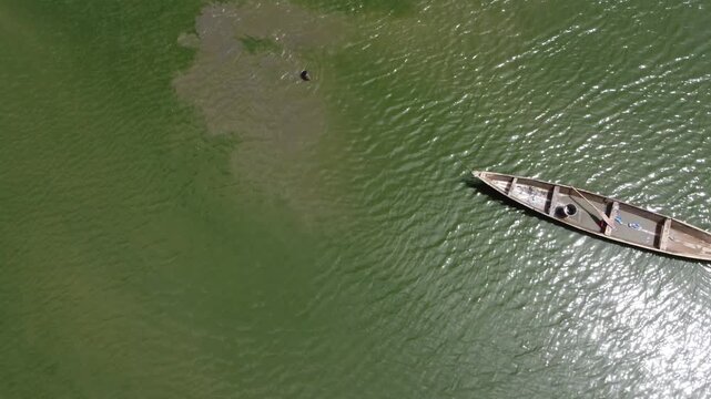 Makurdi, Nigeria - 13 October 2025: Aerial view of a lone boat gliding across the murky waters of the Benue River, leaving a swirling wake behind it.
