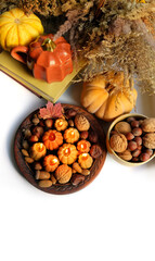 Autumn background. Pumpkin shape cup, nuts, pumpkin, decorative candles, books on white table. cozy composition for fall season, Mabon, Halloween, Thanksgiving holidays. top view. copy space