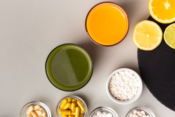 Nutritional supplements, various vitamins and minerals, pills from above on a black stone desk on green background. Smoothie, citrus fruits - lemon, orange and lime as a source of natural vitamins.