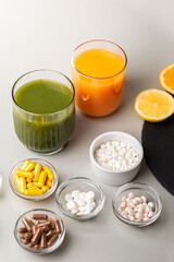 Nutritional supplements, various vitamins and minerals, pills from above on a black stone desk on green background. Smoothie, citrus fruits - lemon, orange and lime as a source of natural vitamins.
